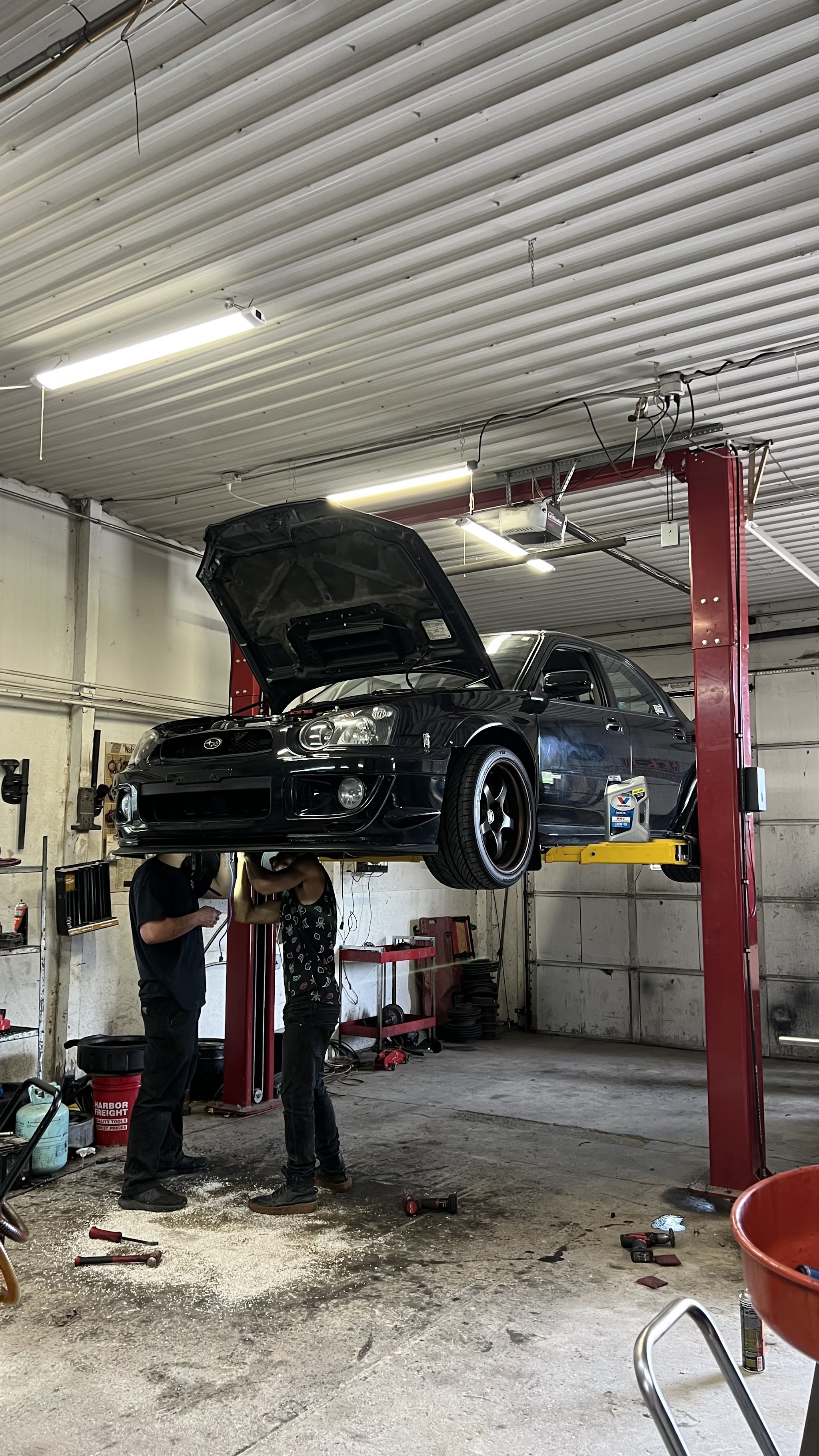 Technicians working under a Subaru on the lift
